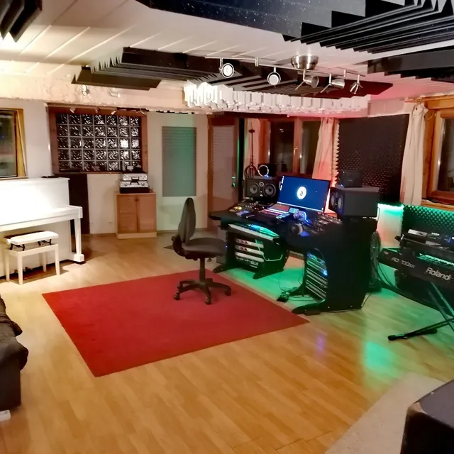 Vue d'ensemble de la Control Room avec piano droit blanc, station de travail, claviers Roland et canapé