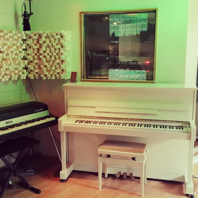 Le Fender Rhodes et le piano droit Kawai dans leur cabine aux diffuseurs en bois